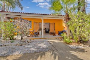 克拉伦代克Tropical Divers Resort的黄色的房屋,设有庭院和棕榈树