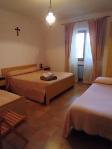 IelsiAgriturismo Masseria Testa Ciruglio的卧室配有两张床,墙上有一个十字架