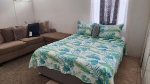 洛尼湾村Caribbean Dream Vacation Property CD3的一间卧室配有一张床和一张带毯子的沙发