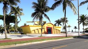 大普拉亚Pousada Casa da Fernanda, Suíte Moon的棕榈树街道上一座黄色的建筑,有红色的门