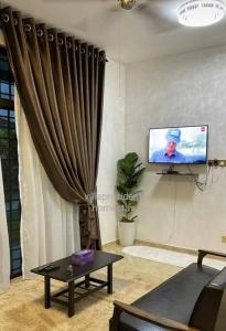 Kampung KerangiVilla President Homestay -4 bedroom Aircond WIFI Vacations Home的带沙发、电视和窗帘的客厅