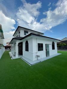 Kampung KerangiVilla President Homestay -4 bedroom Aircond WIFI Vacations Home的一座白色的小房子,设有绿色草坪