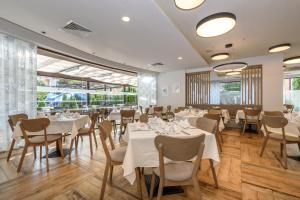 阳光海滩狮阳海滩酒店的餐厅设有白色的桌椅和大窗户。