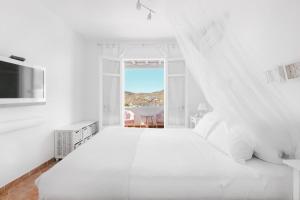 凯勒里瓦迪Mykonian Atmosphere的白色的卧室设有一张白色大床和一个窗户。