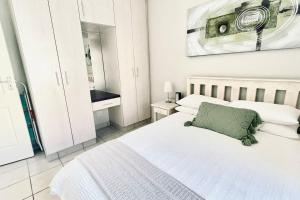 莫塞尔湾Stylish Hartenbos Apartment的卧室配有白色床和绿色枕头