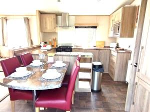 TunstallSand Le Mere Holiday Village Caravan hire的厨房配有桌子和红色椅子