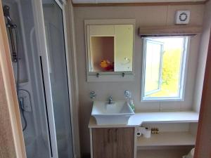 TunstallSand Le Mere Holiday Village Caravan hire的一间带水槽、镜子和淋浴的浴室