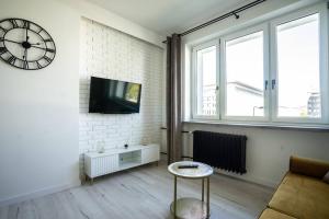 华沙Apartment Marszalkowska Premium Warsaw City Center的一间客厅,在白色砖墙上设有钟表