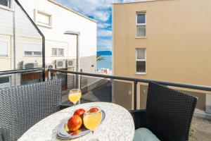 格拉达茨Apartments Mirna Center & Beach的阳台上的桌子上放着两杯橙汁和水果