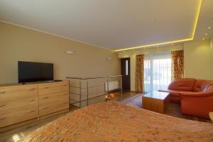 奈达帕斯艾德加拉公寓的一间卧室配有一张床、一台电视和一张沙发