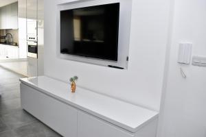 纳杜尔Golden Rays Apartment的白色的厨房设有壁挂式平面电视。