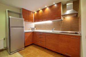 奈达帕斯艾德加拉公寓的厨房配有木制橱柜和不锈钢冰箱。