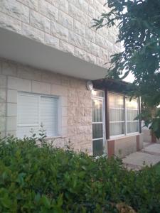 提比里亚LTD Hadas Garden apartment的砖屋,有窗户和灌木