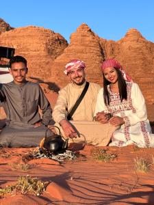 瓦迪拉姆Wadi Rum Oryx Hostel & Tours的一群坐在沙漠中的三人