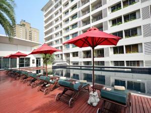 曼谷素坤逸通罗中心站酒店的游泳池旁的一排椅子和遮阳伞