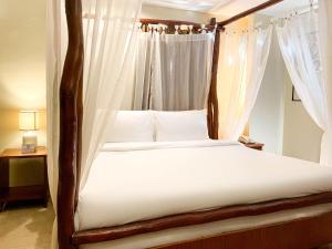 长滩岛Serene La Playa Boracay的卧室配有带白色床单和枕头的天蓬床。