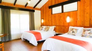 圣赫拉多德多塔蒙大拿苏利亚酒店的配有木墙和窗户的客房内的两张床