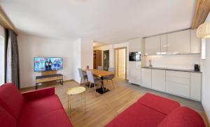 萨姆瑙恩Aparthotel Grischuna的一间带红色沙发的客厅和一间厨房