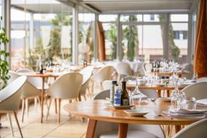 佩皮尼昂Holiday Inn Perpignan, an IHG Hotel的餐厅设有木桌、椅子和窗户。