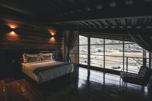 瓜达鲁佩镇Origen75 Loft - Villas - Skypool - Viñedo, Valle de Guadalupe的卧室配有床、椅子和窗户。