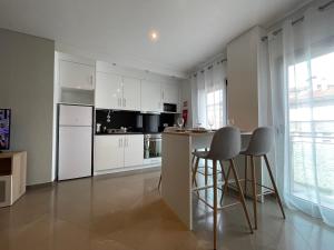法蒂玛Fátima Apartment - 1min Santuário的厨房配有白色橱柜、桌子和凳子