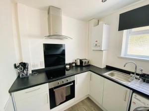 斯旺西Emerald Properties UK 4 bedrooms - Swansea City Centre, close to beaches!的厨房配有白色橱柜和黑色台面