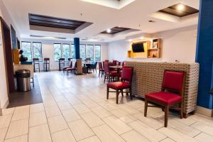 歌珊戈申快捷假日&套房酒店的一间设有红色椅子的用餐室和一间酒吧