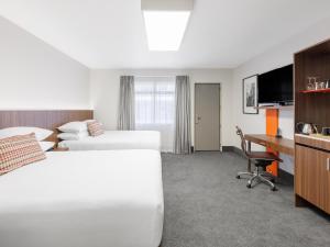 汉密尔顿JetPark Hamilton Airport New Zealand的酒店客房配有两张床和一张书桌