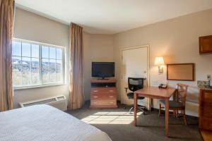 降落伞Western Slope Suites Parachute的酒店客房配有一张床、一张书桌和一台电视。
