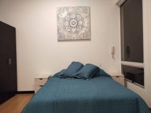 波哥大Espectacular Dúplex moderno的卧室配有一张蓝色的床,墙上挂着一幅画