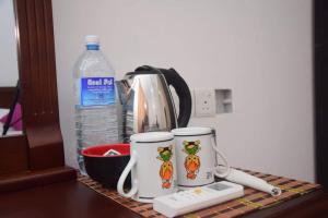 尼甘布塞林迪村宾馆的配有2个咖啡杯和1瓶水的吧台