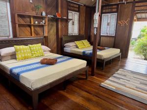 刁曼岛Swiss Cottage Tioman的配有木墙和木地板的客房中的两张床