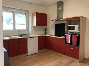 Plonéour-LanvernCocon familial dans le Pays Bigouden !的厨房配有红色橱柜、水槽和微波炉