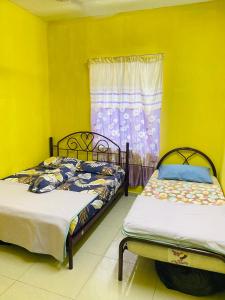 Kampong Alor GajahHomestay Zalida C Musleem的配有两张床的客房,设有黄色的墙壁和窗户