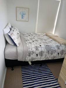 旺阿帕劳阿Adorable Beach Unit Stanmore Bay的一间卧室配有一张带毯子和地毯的床