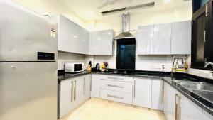 新德里大凯拉什奥利弗服务式公寓的厨房配有白色橱柜和冰箱。