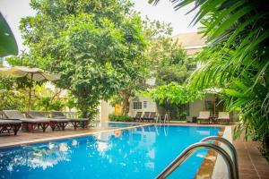 金边天际线精品酒店的一个带桌椅和树木的游泳池