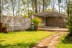 奈瓦沙Stone Camp Naivasha的一个带长凳和大遮阳伞的花园