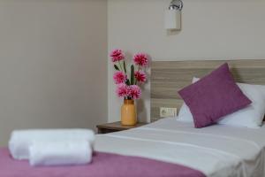 巴统黛丝日落酒店的一张带花瓶的床,上面有粉红色的花朵