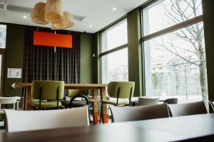奥贝维利埃easyHotel Paris Nord Aubervilliers的一间拥有绿色墙壁和桌椅的用餐室