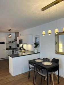 波鸿Moderne Wohnung mit 4 Betten的一间带黑色桌椅的厨房和一间带白色橱柜的厨房