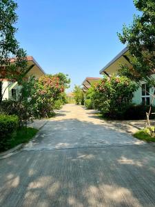 Kaeng KhoiMe and Tree Villa的两座房子之间一条空的路,有粉红色的花