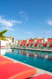 马略卡岛帕尔马The Boc Hostels - City的一个带椅子的游泳池以及位于后面的建筑