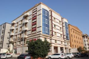 吉达Altamyoiz Sirved Apartments的一座高大的建筑,前面有汽车停放