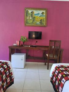 罗威那罗威那海滩酒店的客房设有书桌和粉红色墙壁上的电视