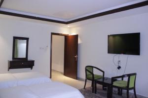 吉达Altamyoiz Sirved Apartments的一间卧室设有两张床,墙上配有电视。