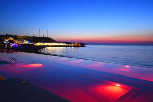 凯里尼亚Acapulco Resort Hotel的日落时分享有海滩美景,设有游泳池