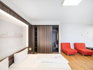 海德堡博丁哈斯7天酒店的一间卧室配有一张床和两张红色椅子