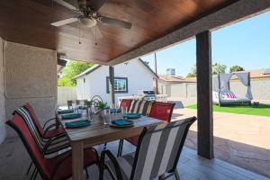 凤凰城Relaxing Oasis: Spacious 4BR House w/ Private Pool的庭院内一张带椅子的木桌和吊扇