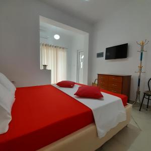 萨兰达Denni’s Home的卧室配有红色和白色的床和电视。